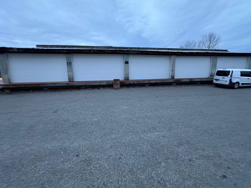 Multi-bay commercial storage facility with row of white garage doors wide view